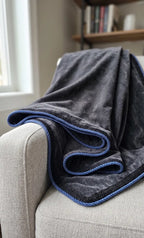 Cordão de algodão preto com vivo azul, em detalhe sobre tecido claro, numa coberta 
