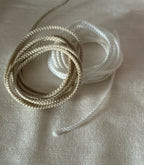 Coiled beige and white braided cordão fio de luz filamento 100% branco natural with brilho acetinado and seda técnica texture