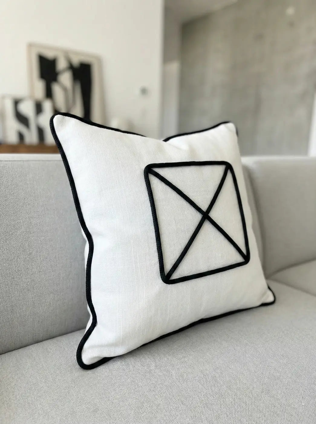 Almofada de linho branco com design geométrico bordado em preto e cordão grafite em contraste gráfico l&l