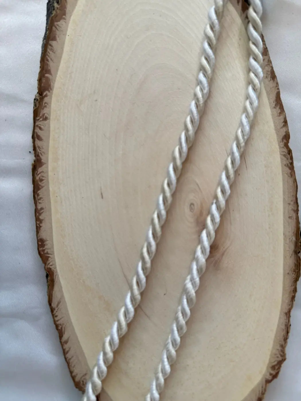 Cordão grand duke branco torcido em filamento 5mm 6mm sobre base de madeira clara