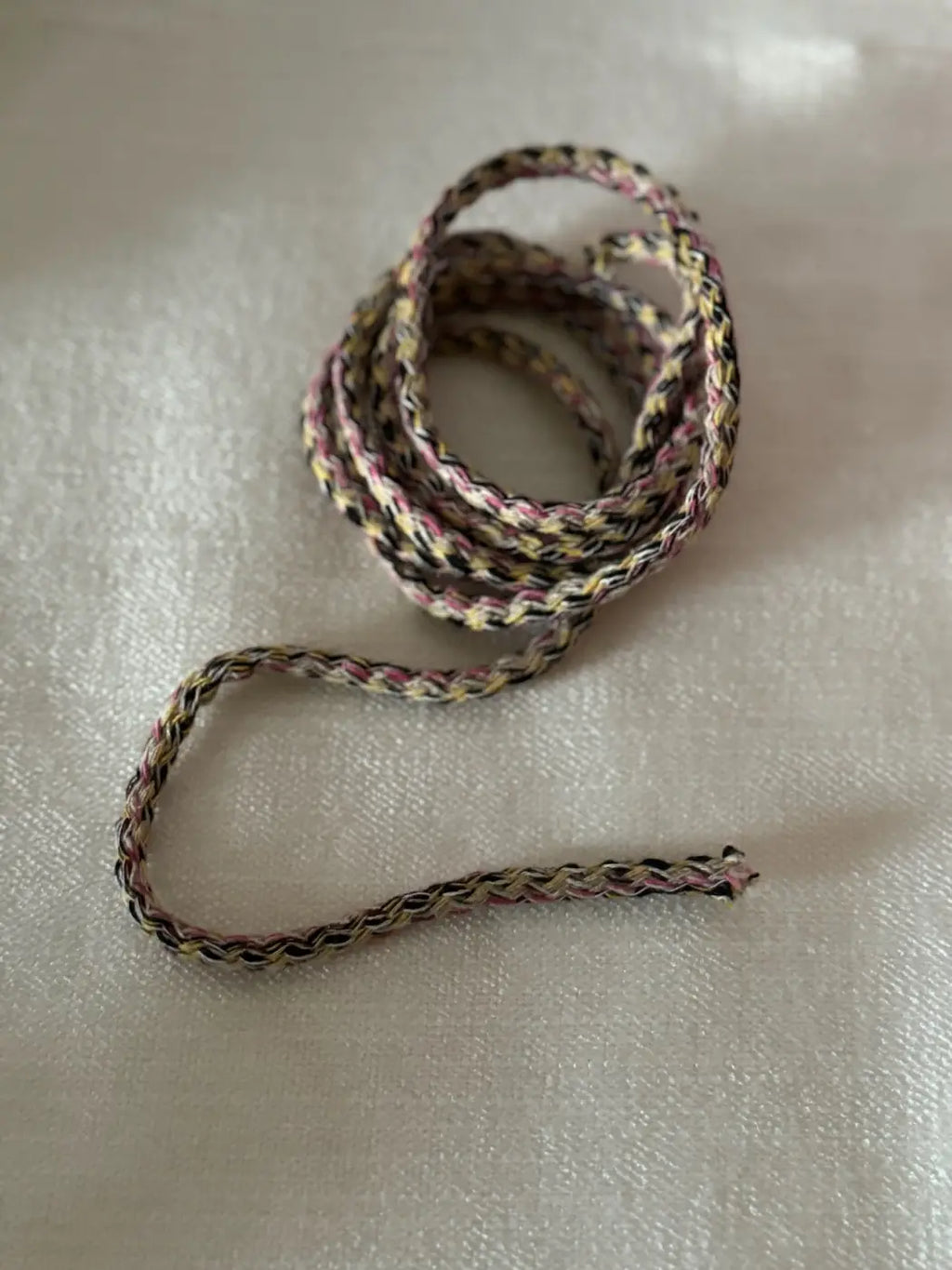 Cordão vivo multicolor em cordão trançado com padrão preto, rosa e bege ideal para projetos criativos