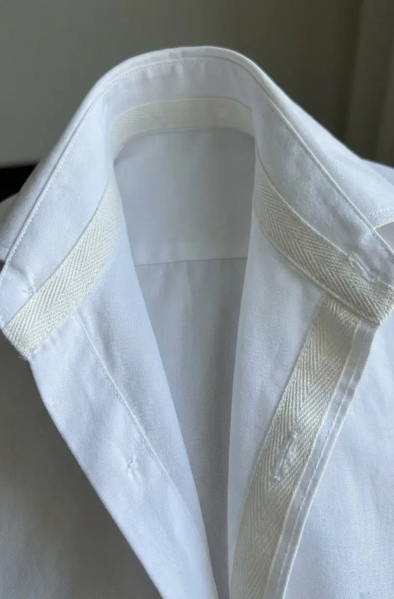 Camisa branca com toque suave em poliéster 100% com detalhe em espinha creme no colarinho e pala