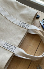 Beige bolsa de lona com padrão em quadrados pretos bordados nas pegas feita em fita tafetá de poliéster 35mm cru