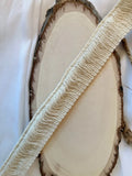 Franja plissé natural em algodão 100 por cento creme com borda texturada e desfiada sobre fatia de madeira rústica