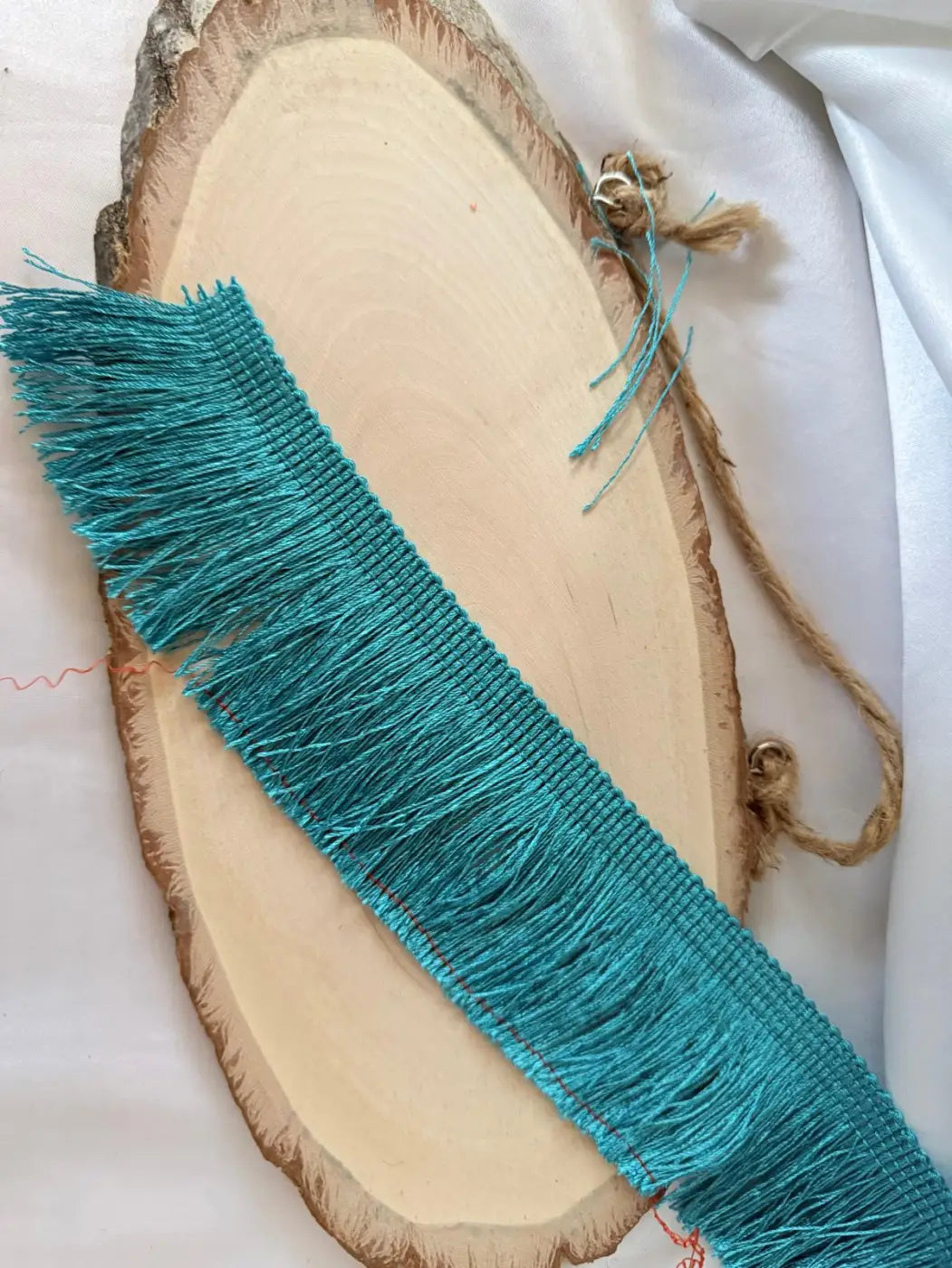 Franja gatsby em rayon seda vibrante azul turquesa com textura tecida exibida em fatia rústica de madeira