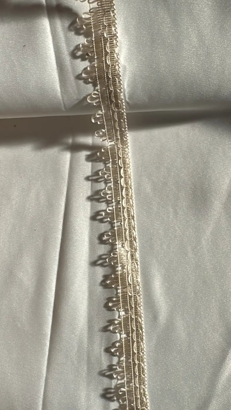 Franja luar acetinado em renda creme delicada com padrão floral intricado e textura fina em filamento 25mm