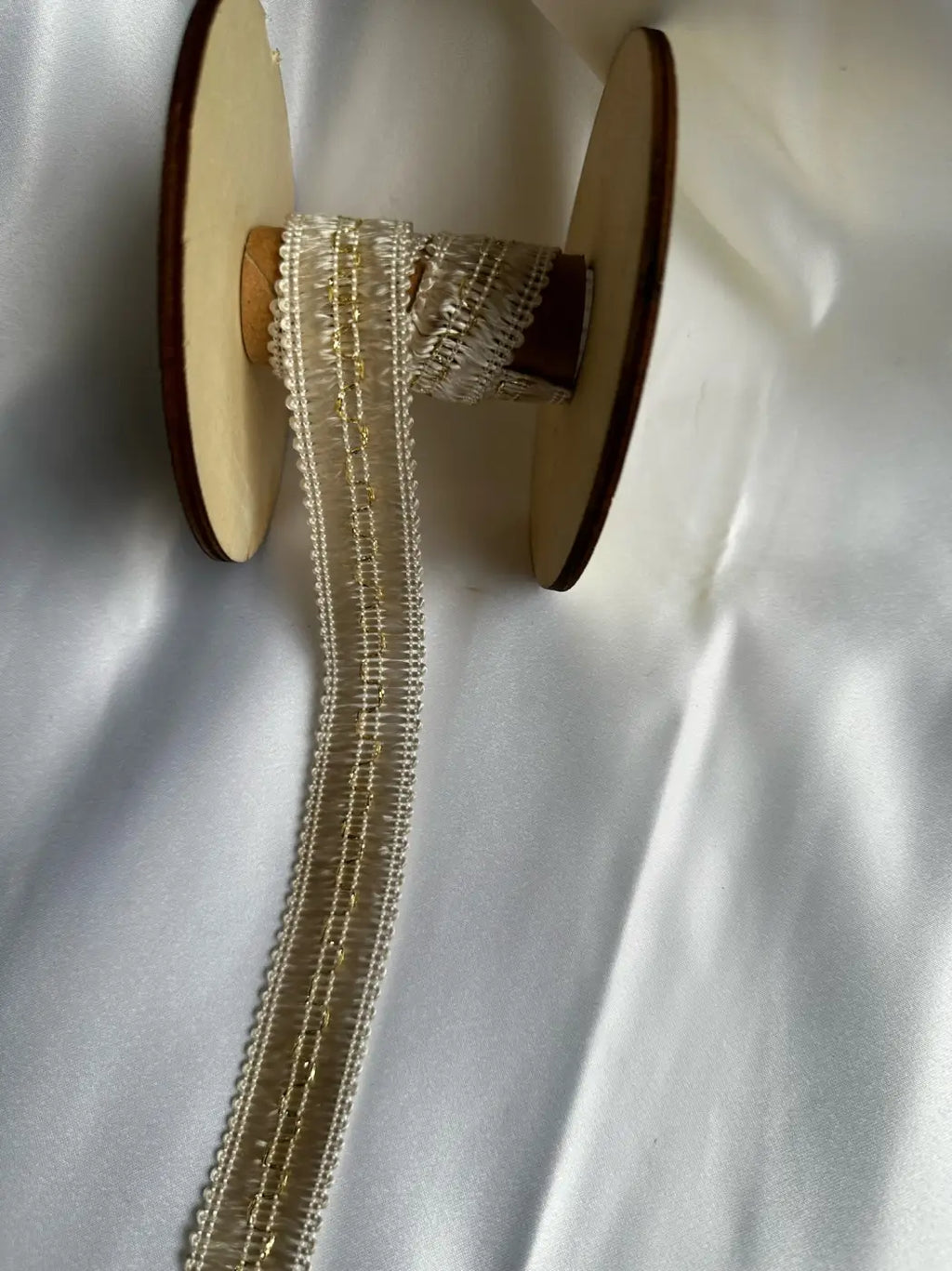 Galão ducale filamento 80% 25mm em renda off-white com brilho metálico dourado e alma estrutural em carretel de madeira