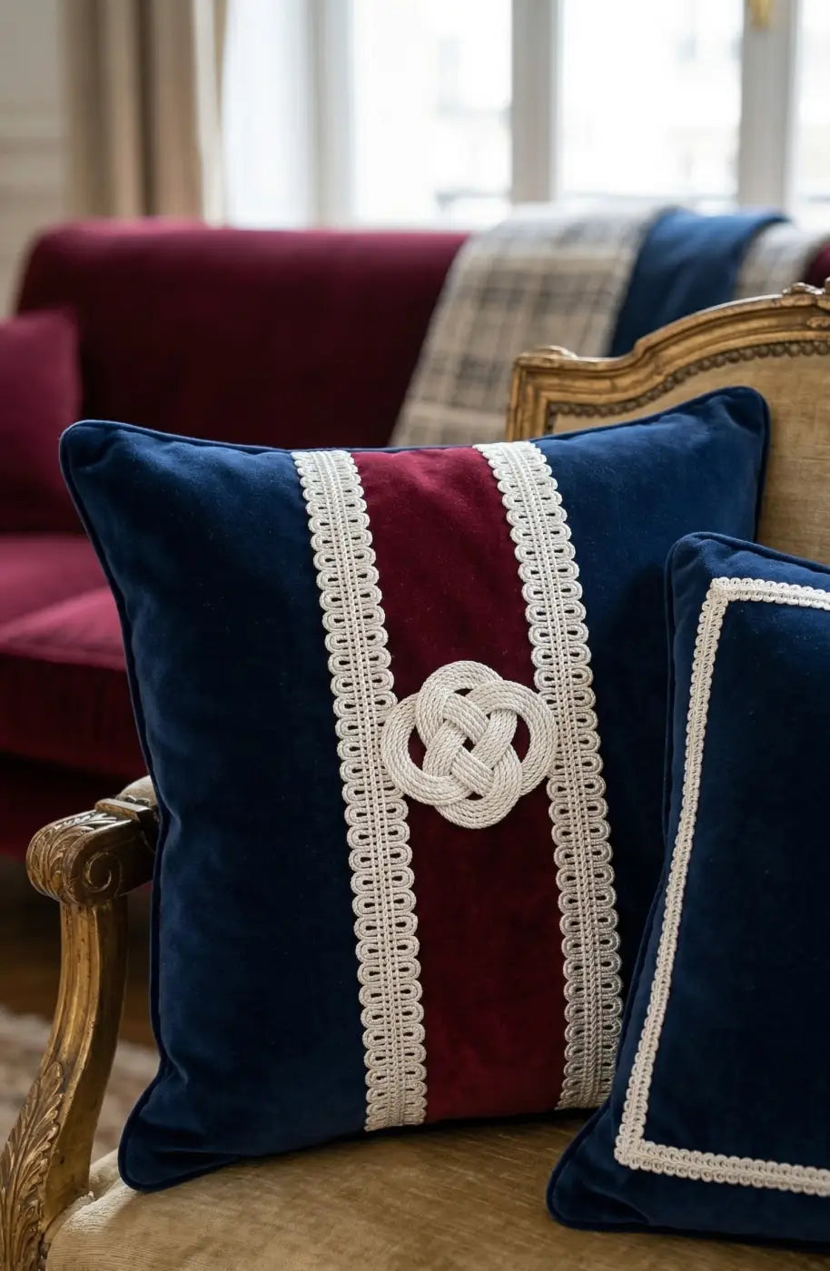 Navy blue velvet throw pillow with burgundy stripe, white lace trim, and embroidered celtic knot featuring galão vendôme
