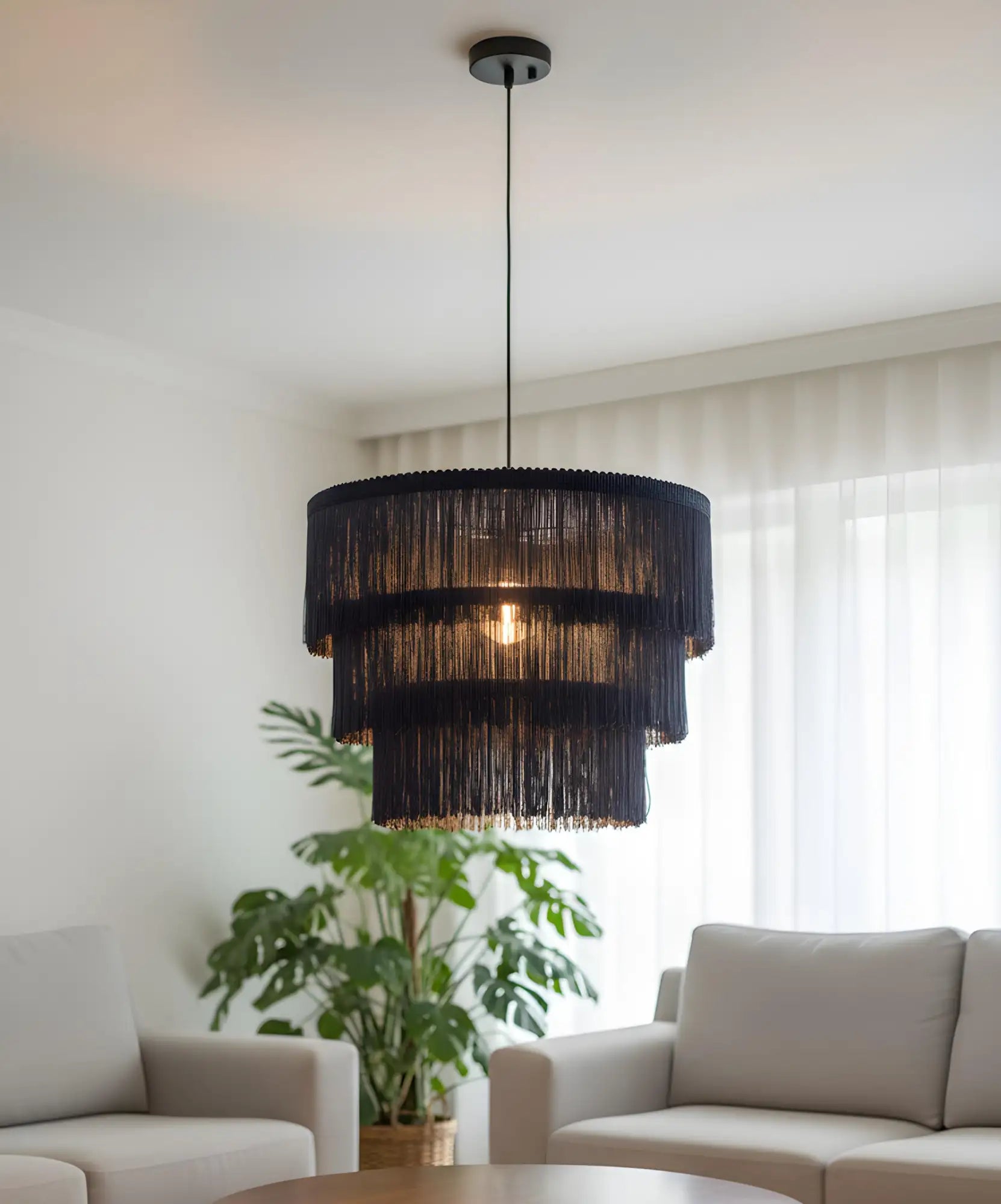 Luminária pendente com franja em camadas preta e luz quente.